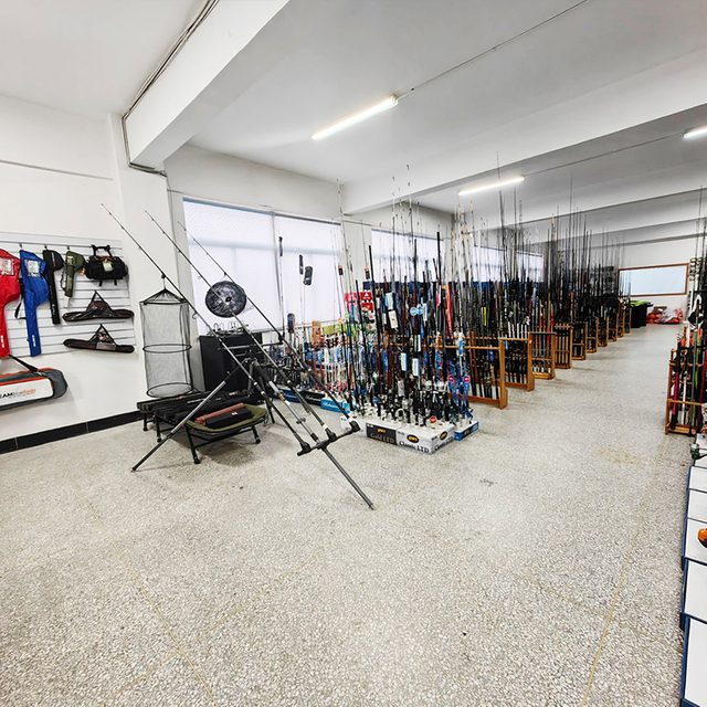 Interior view of a well-stocked fishing store displaying a wide range of fishing rods, including carbon fiber models, along with fishing reels and lures.