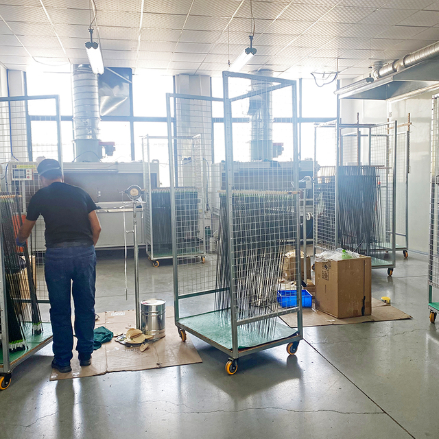 Factory interior showcasing the production process of carbon fiber fishing rods, with workers handling equipment and finished products ready for assembly with reels and lures.